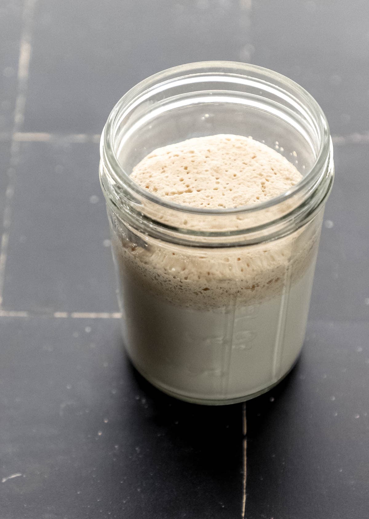 Close up side view of activated yeast and milk in glass jar. 