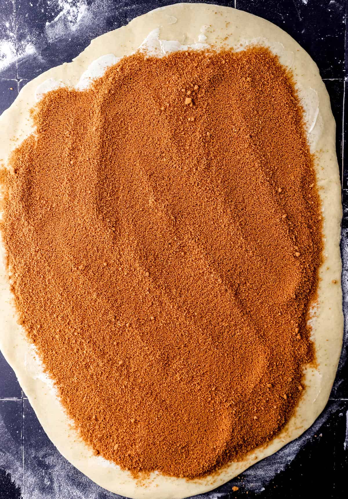 Overhead view of dough rolled out and topped with butter, cinnamon, and brown sugar. 