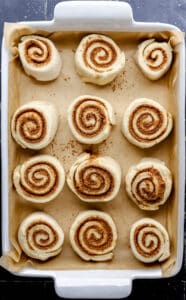 Cut cinnamon rolls added to parchment lined baking dish.