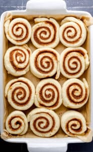 Overhead view of cinnamon rolls after rising in baking dish.