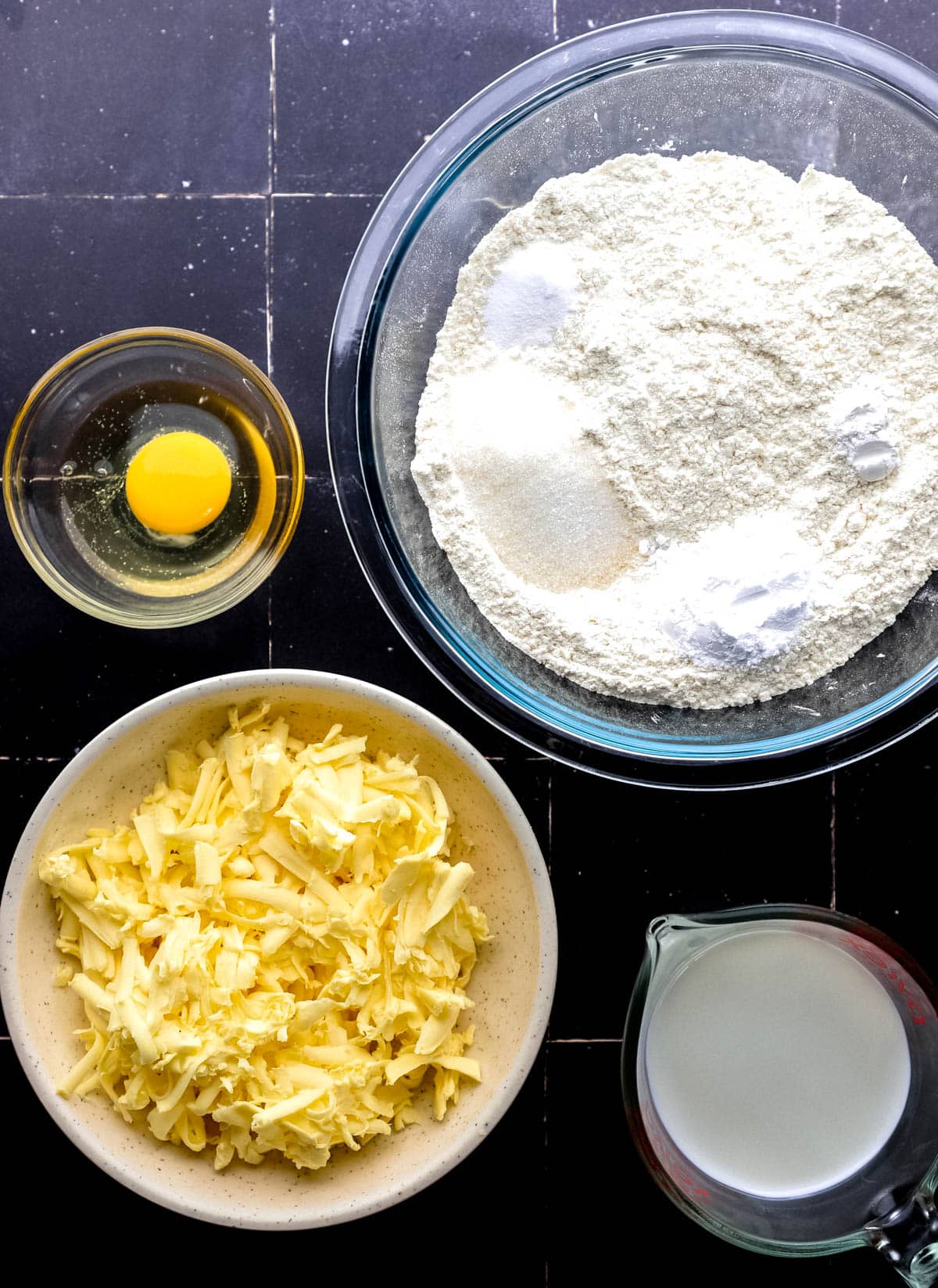 Overhead view of ingredients needed to make biscuits in separate bowls. 