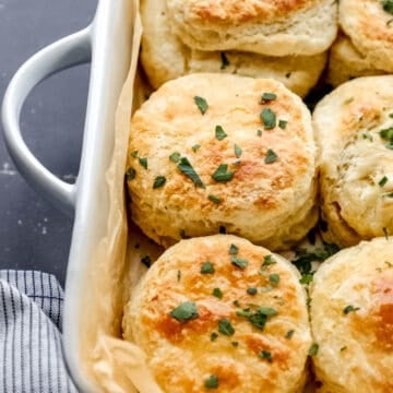 Close up view of biscuits in parchment lined baking dish by a cloth napkin.