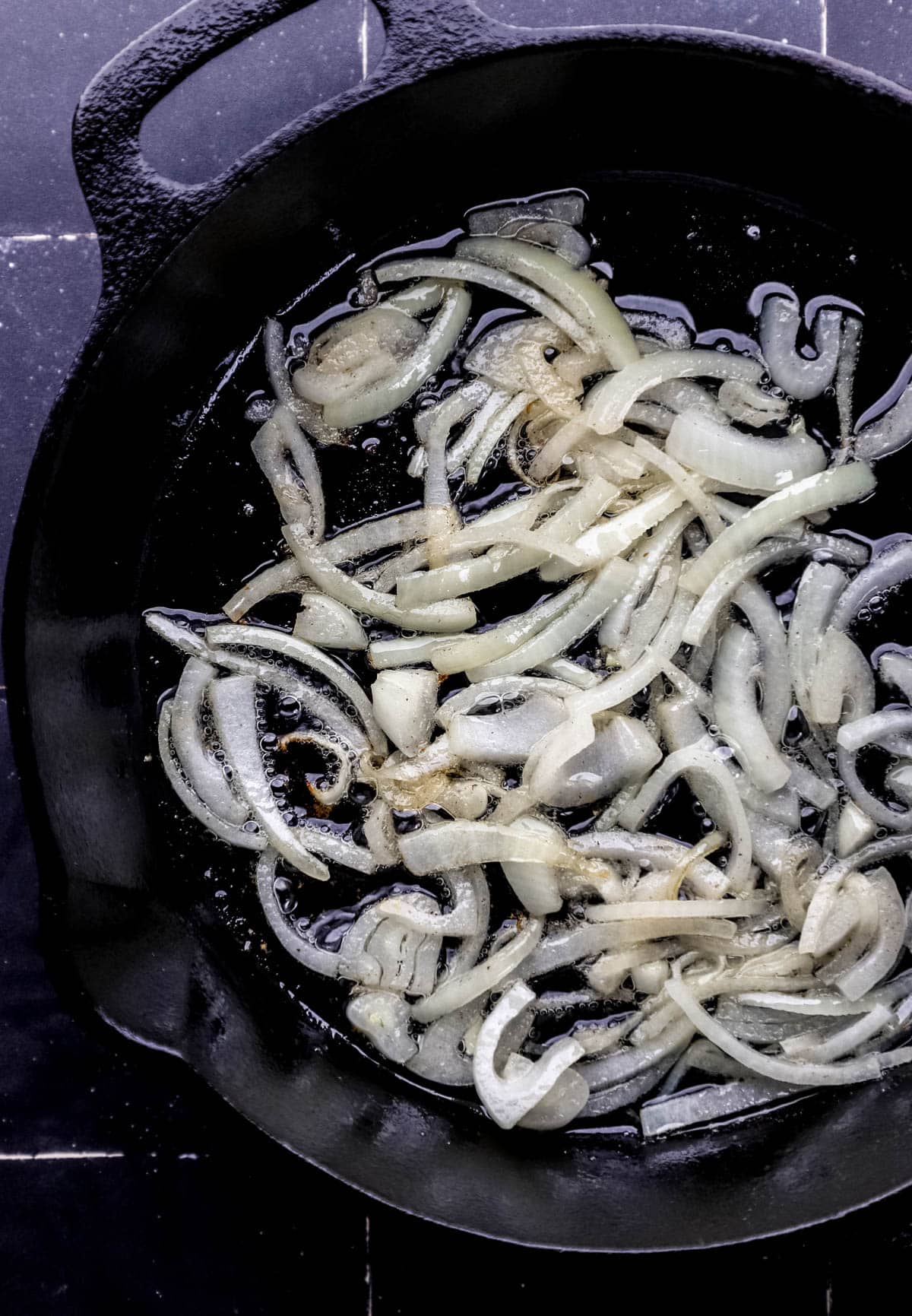 Sliced onion, oil, and butter in cast iron skillet. 