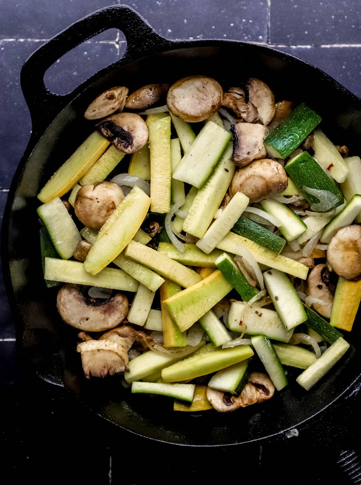 Overhead view of sliced veggies in cast iron skillet. 