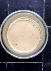 Overhead view of yum yum sauce in jar on black tile surface.