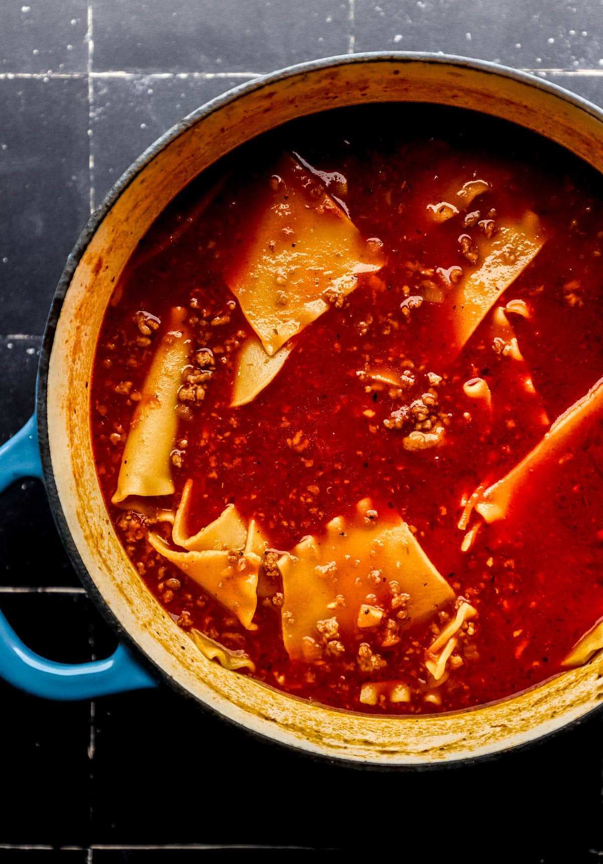 Finished lasagna soup in large pot on black tile surface. 