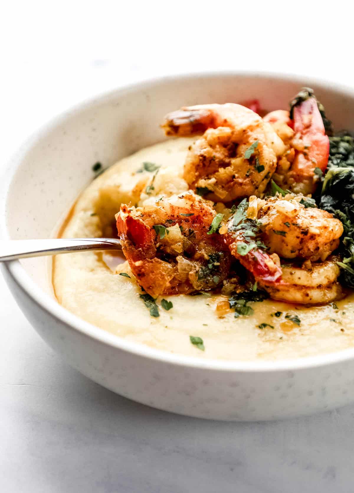 Close up side view of a bowl of shrimp and cheese grits. 
