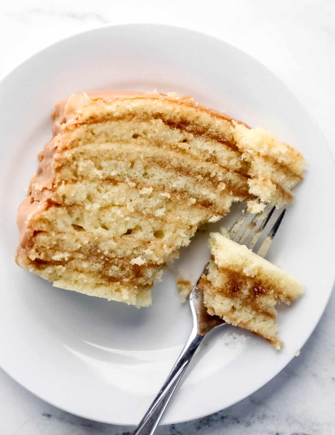 Overhead view of slice of cake on white plate with fork in it. 