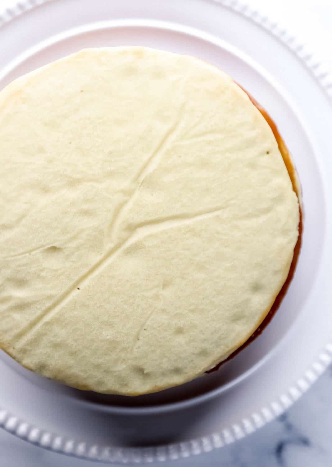 Cake layers stacked on top of each other on white cake plate. 