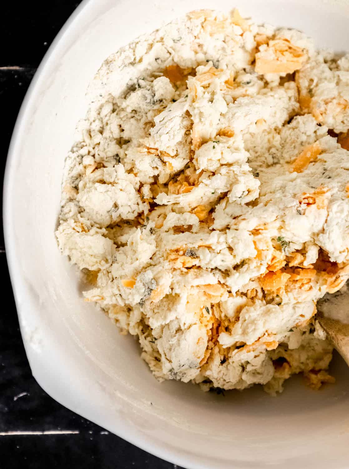 Biscuit ingredients combined in large white mixing bowl to form loose dough. 