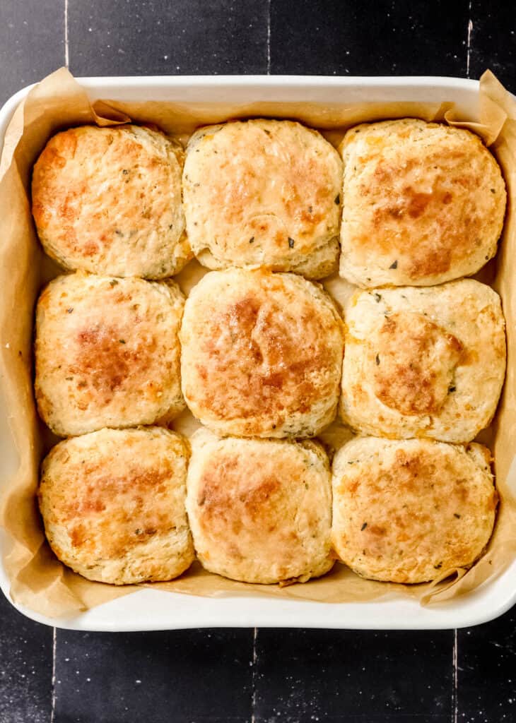 Overhead view of biscuits in a white parchment lined baking dish.