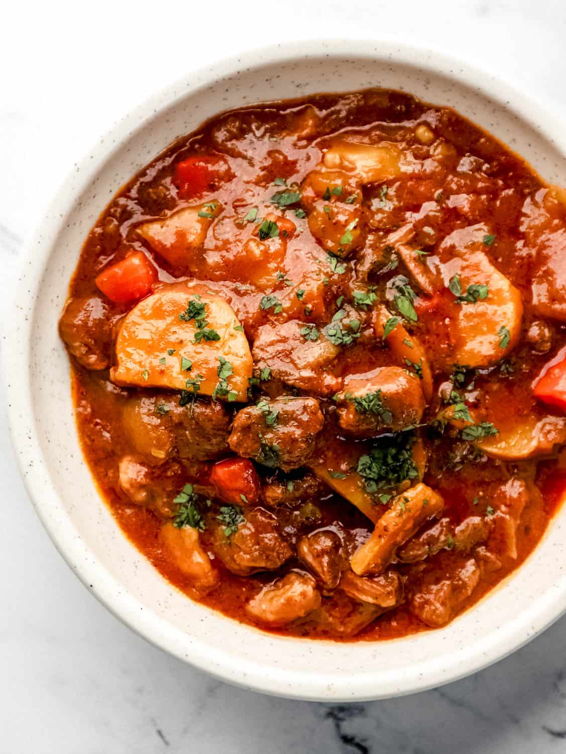 Overhead view of bowl of stew topped with freshly chopped parsley on to of it. 