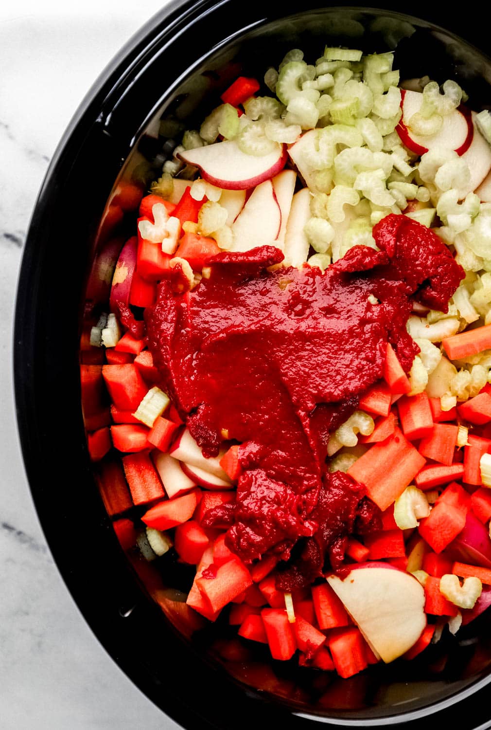 Tomato paste added to the top of the ingredients to make the beef stew in the crock pot. 