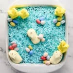 Overhead view of easter dirt pudding in white square dish on marble surface.