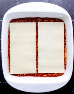 Meat sauce and noodles in square baking dish.