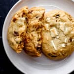 Overhead view of two cookies on white plate with one cookie broke in half.
