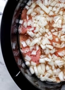 Chopped onion added to the crock pot with the other ingredients.