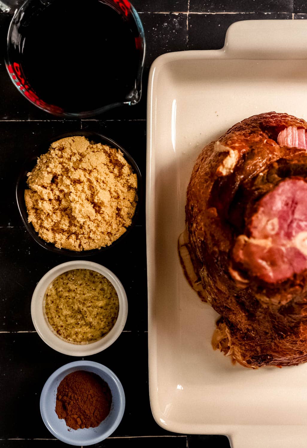Overhead view of ingredients needed to make glazed ham in separate bowls. 