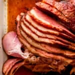 Overhead view of sliced ham in white baking dish.