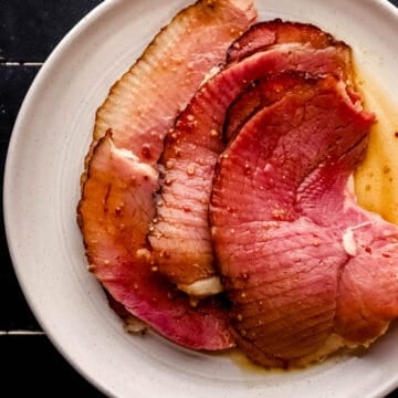 Overhead view of slices of ham covered in glaze on white plate.