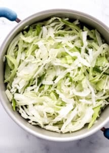 Overhead view of sliced cabbage in large pot.