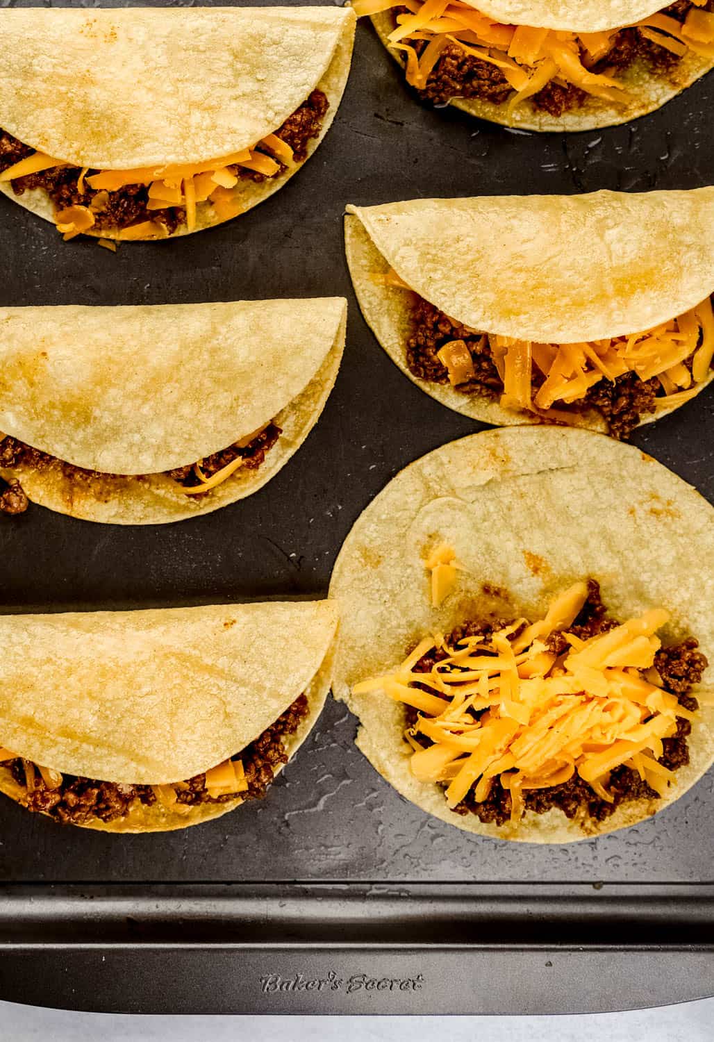 Assembled tacos on oiled baking sheet before baking. 