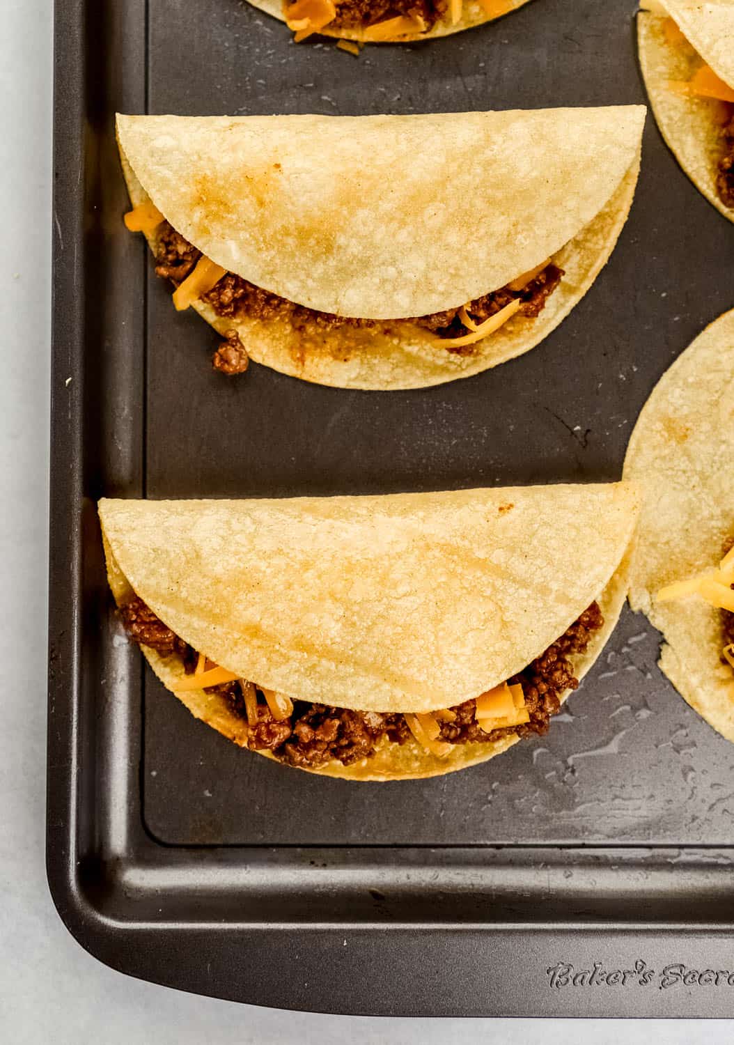 Unbaked tacos on baking sheet before baking. 