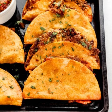 Close up front view of baked tacos on baking sheet.