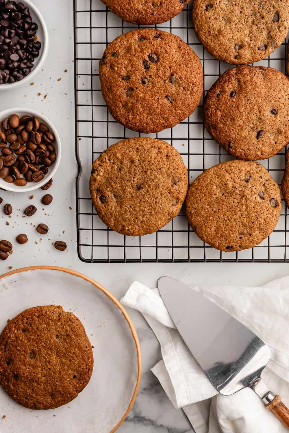 Finished cookies on rack and plate by small bowl of coffee beans.