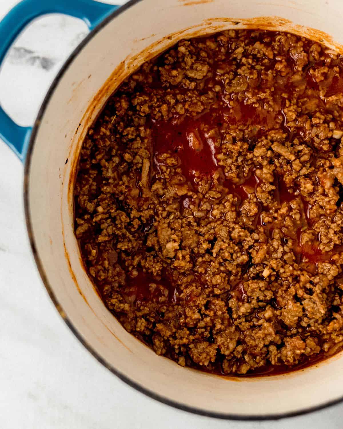 Meat sauce in a large stock pot on marble surface. 