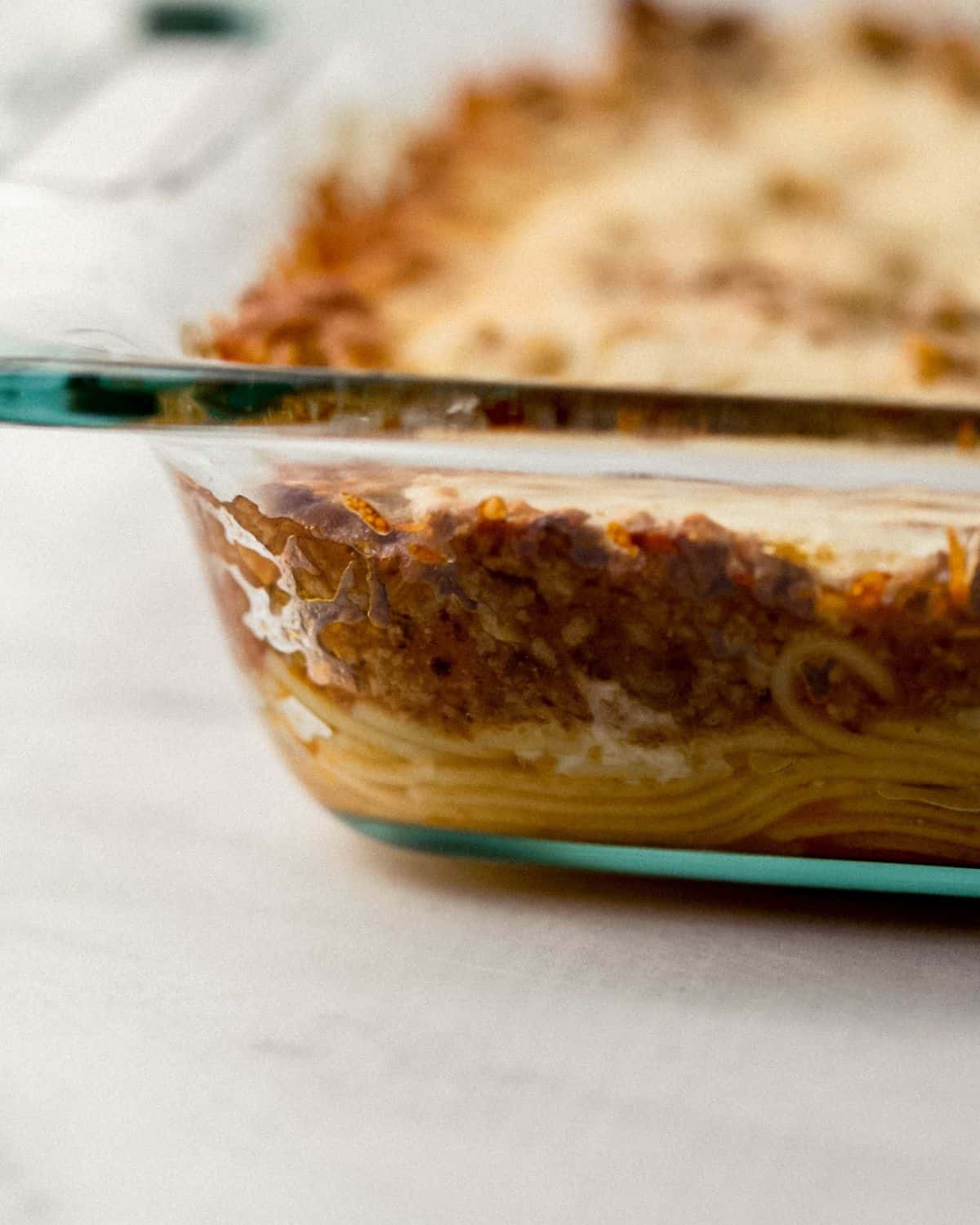 Close up side view of finished spaghetti in glass baking dish. 