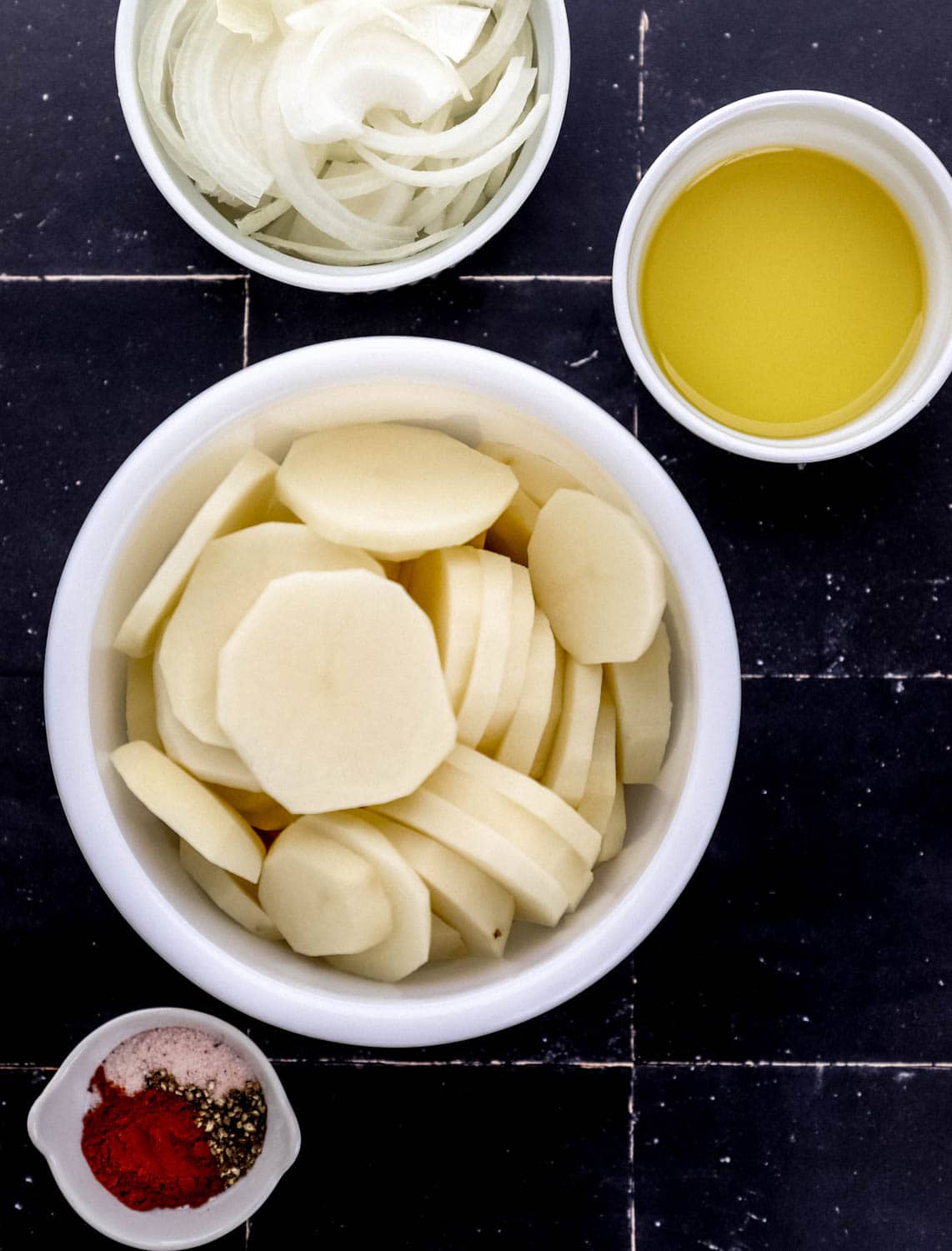 Overhead view of four bowls with ingredients needed to make potatoes. 