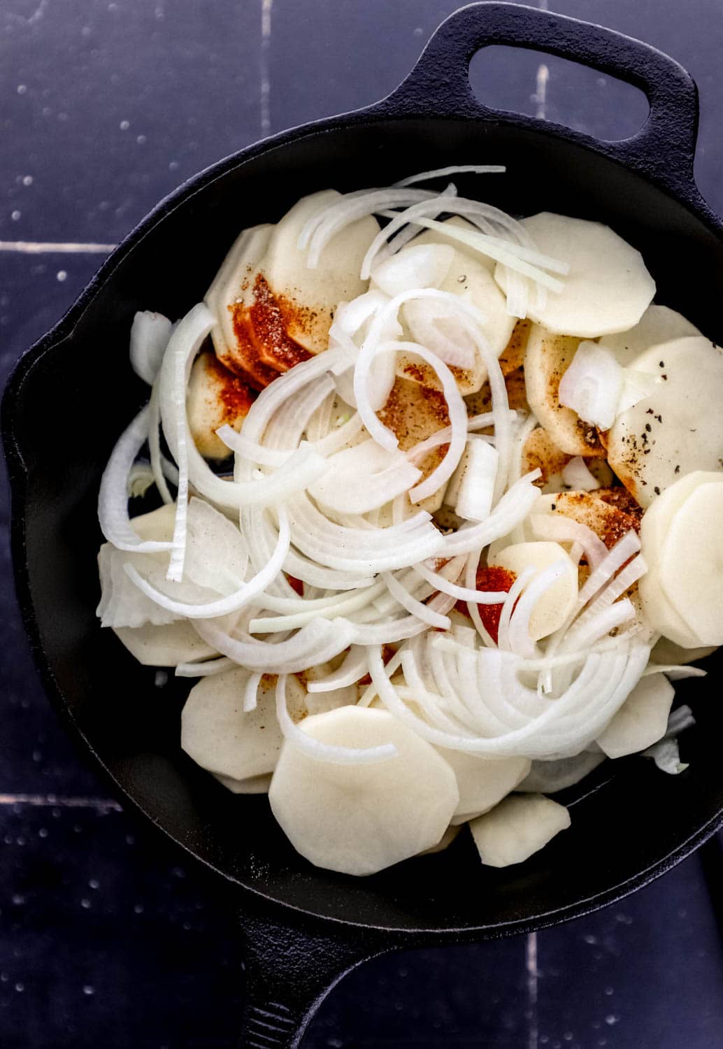 Overhead view of ingredients to make potatoes in cast iron skillet. 