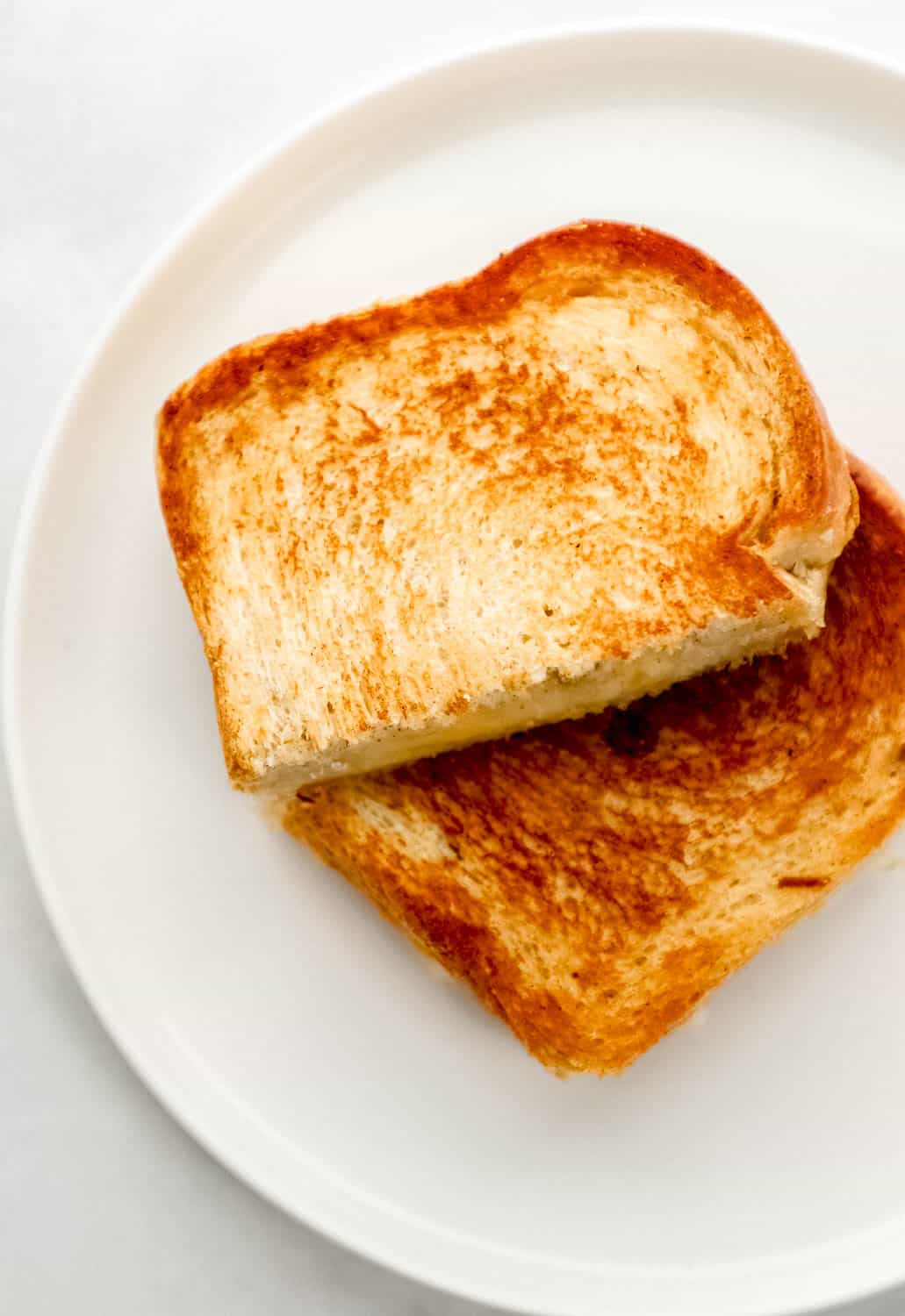 Sandwich cut in half on white plate. 