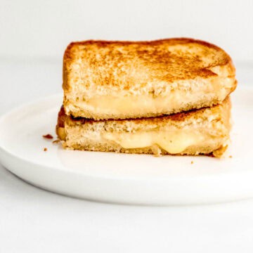 Close up front view on sandwich cut in half and stacked on white plate.