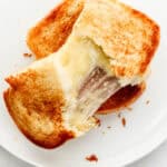 Overhead view of cheese sandwich on white plate pulled apart.