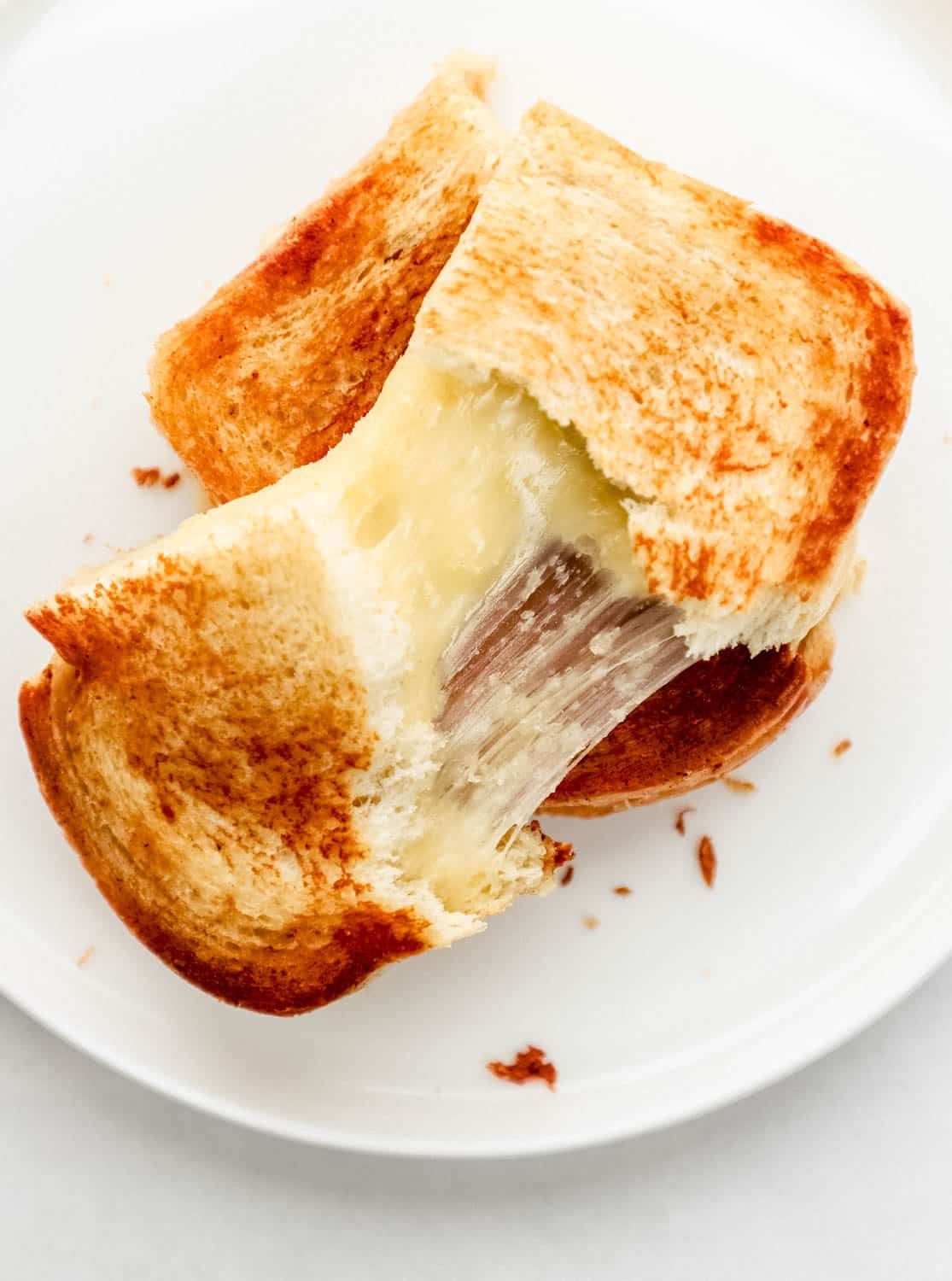 Overhead view of sandwich on with plate with half of it pulled in half with cheese. 