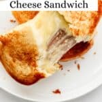 Overhead view of cheese sandwich pulled apart on white plate pin with text overlay.