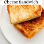 Overhead view of finished sandwich cut in half on white plate pin with text overlay.