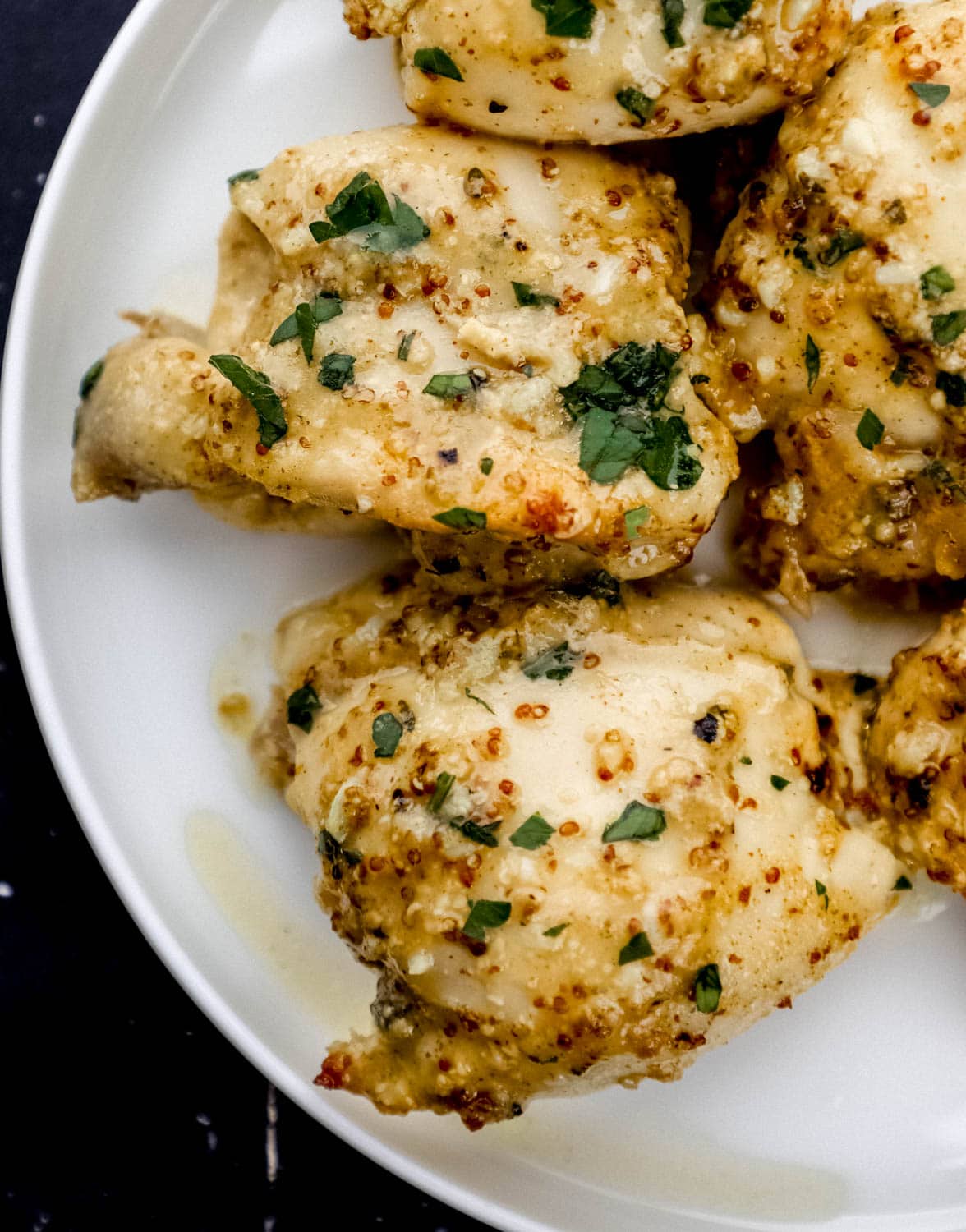 Overhead view of finished chicken topped with chopped parsley on white plate. 