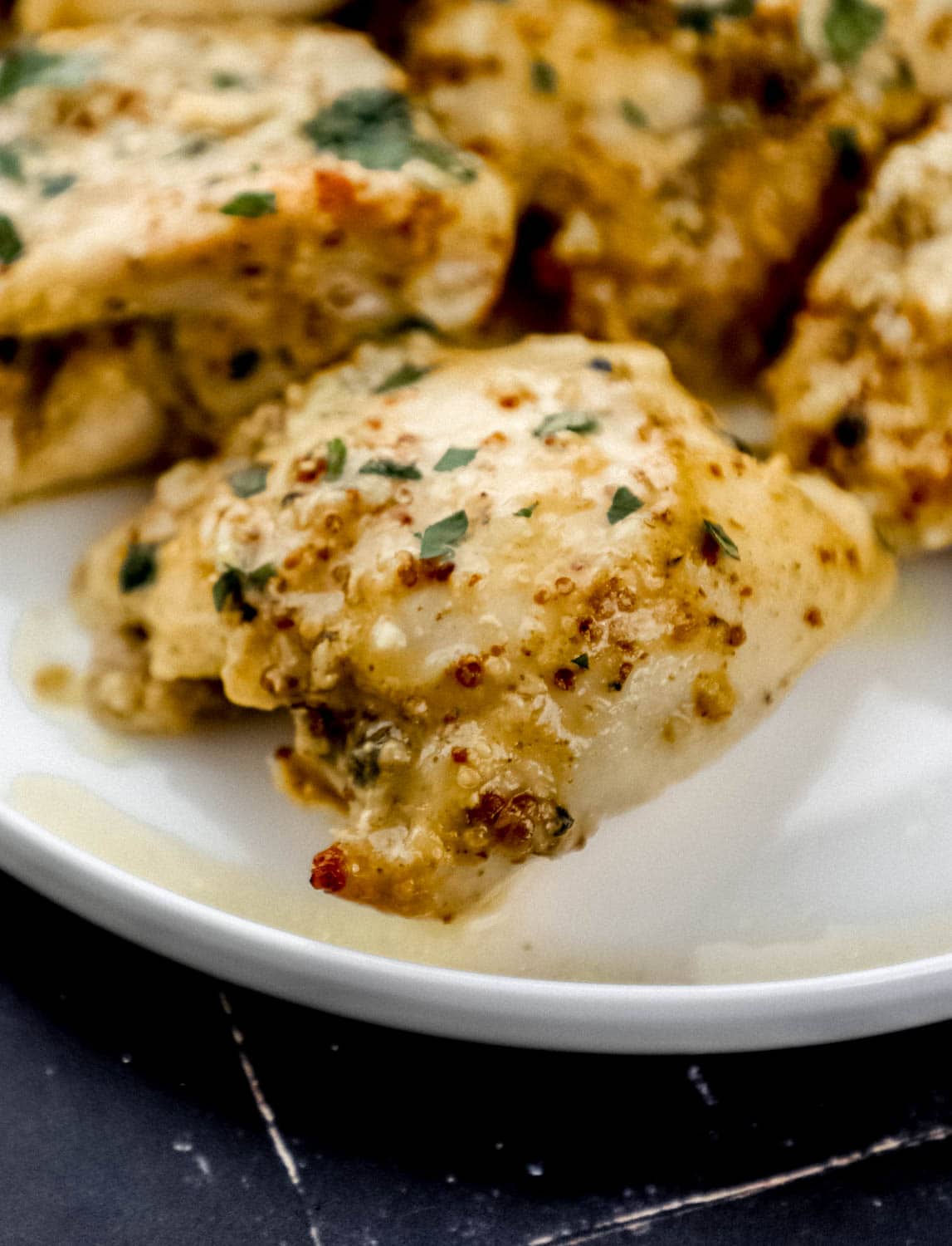 Close up front view of baked chicken on white plate. 