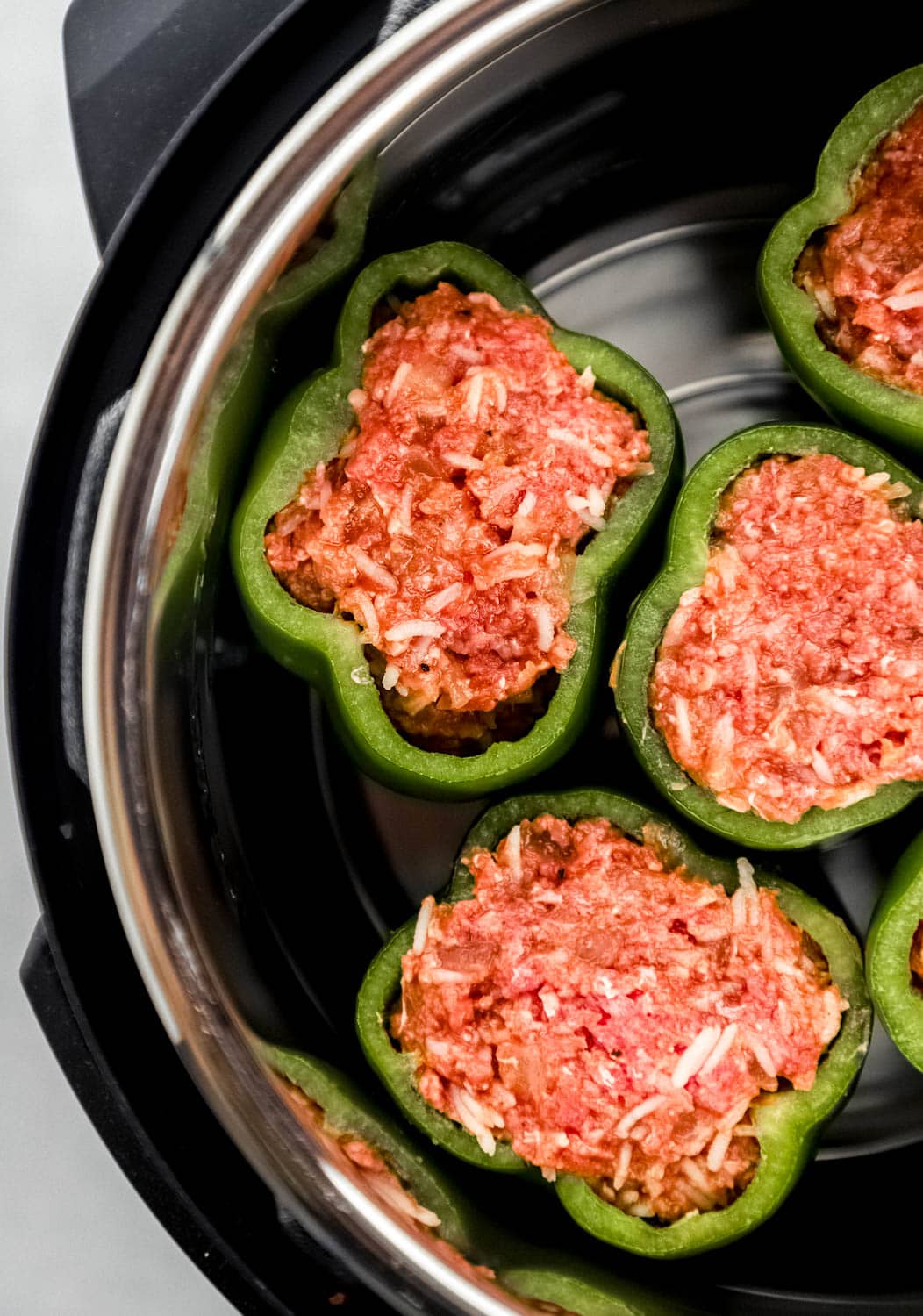 Overhead view of stuffed peppers in instant pot before cooking. 