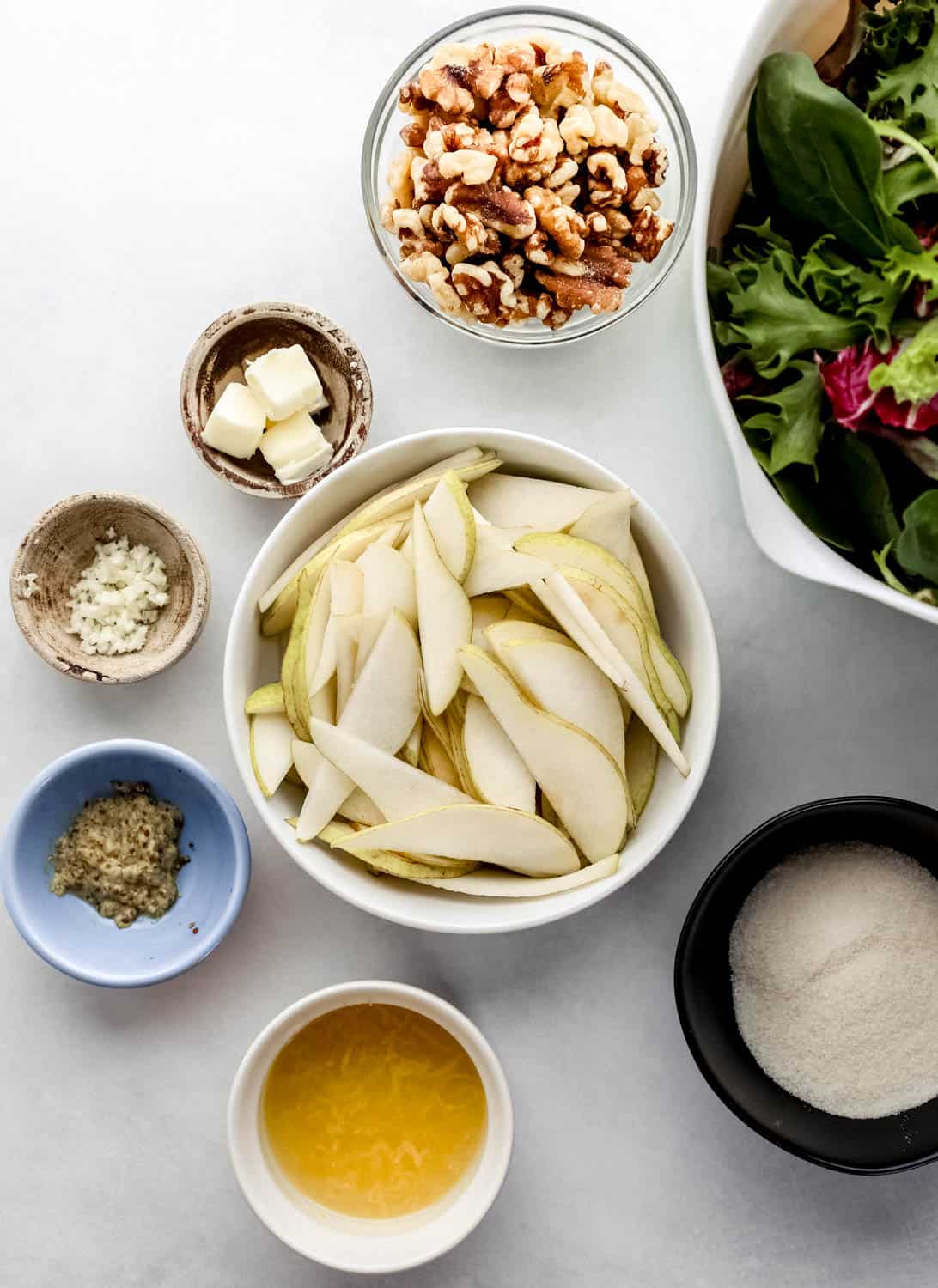 Overhead view of ingredients needed to make salad in separate bowls on white surface. 