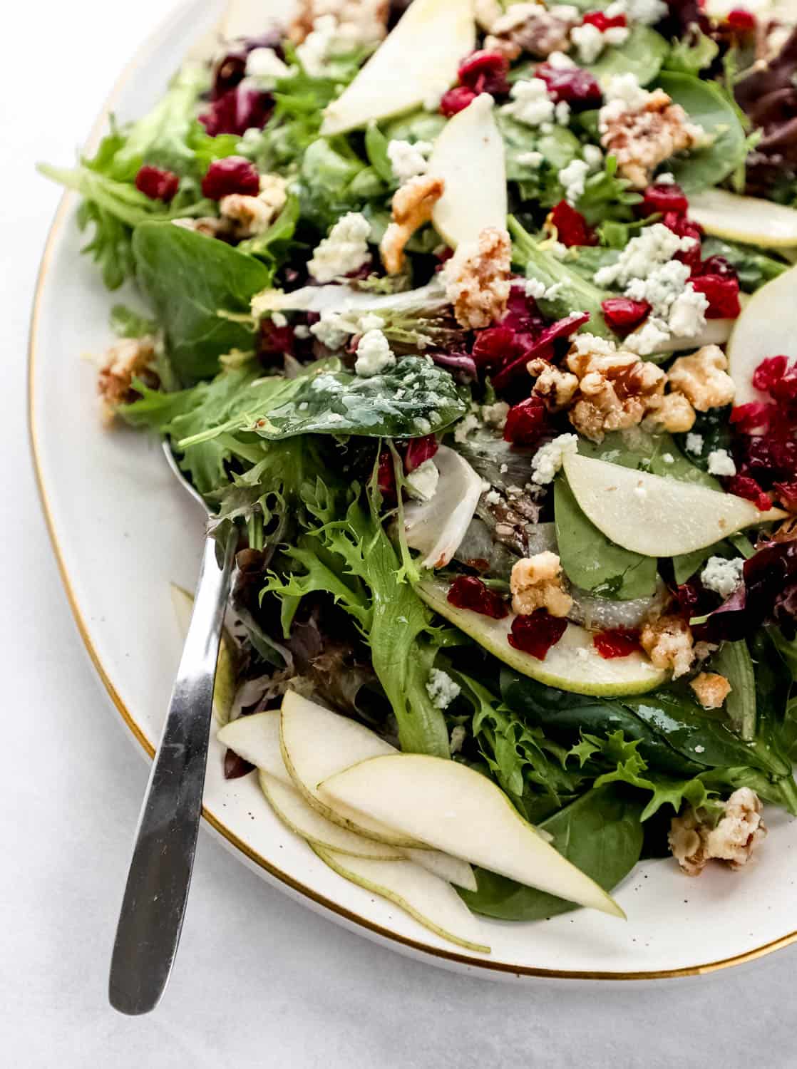 Close up front view of finished salad on platter with serving spoon in it. 