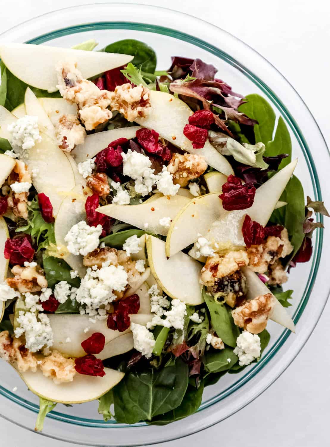 Finished salad in large glass mixing bowl topped with blue cheese crumbles. 