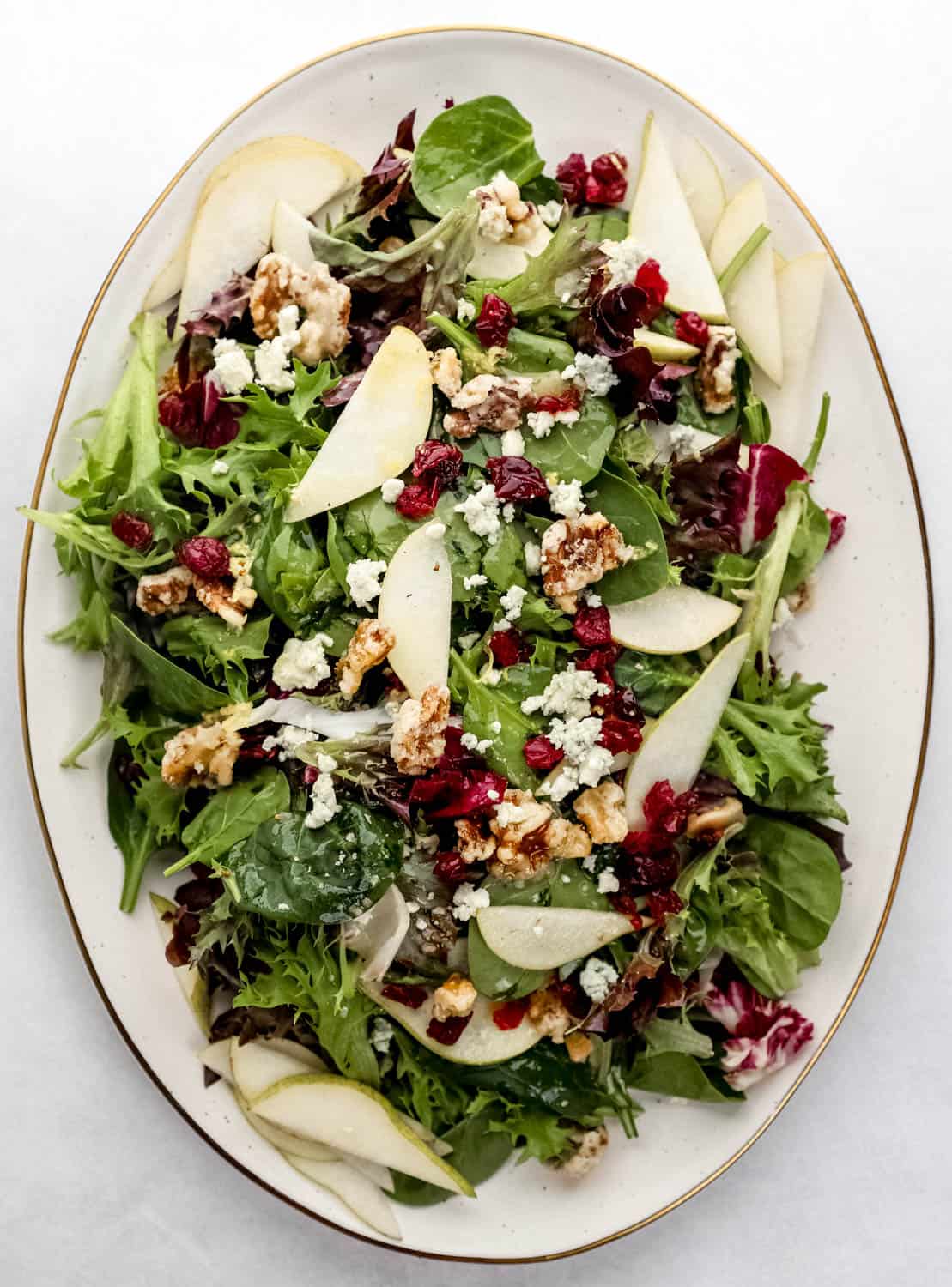 Overhead view of platter with finished salad on it on white surface. 