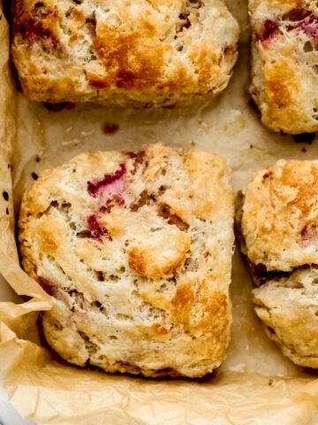 Overhead view of baked strawberry biscuits in white parchment lined baking dish.