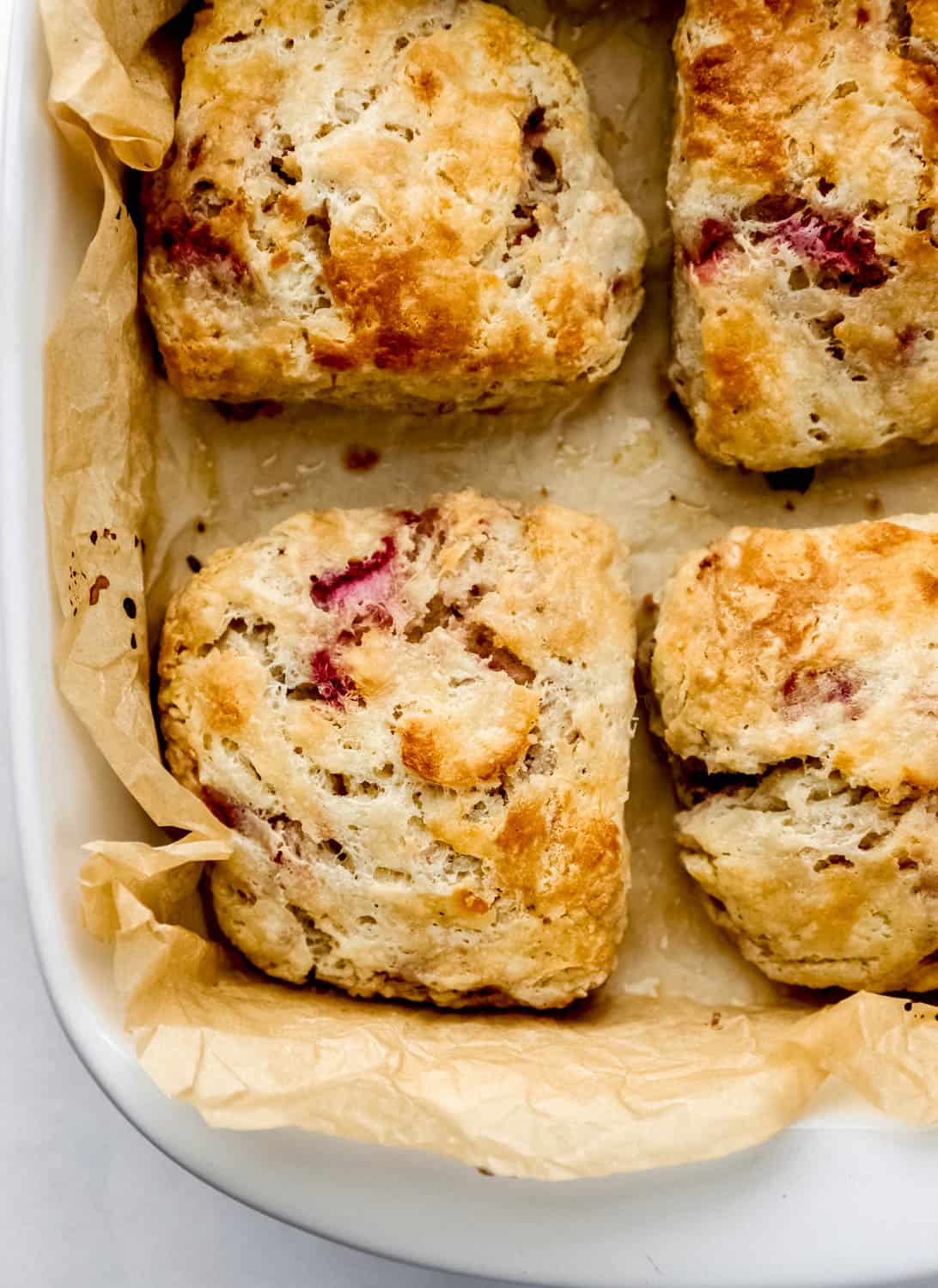 Overhead view of strawberry biscuits in parchment lined baking dish. 