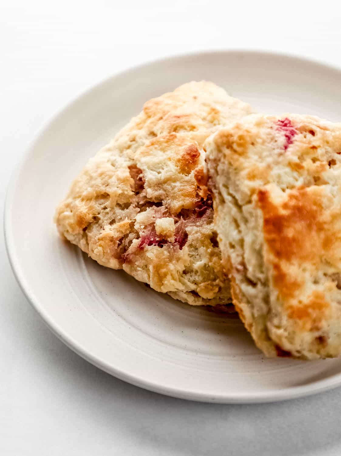 Close up side view of two biscuits on white plate. 