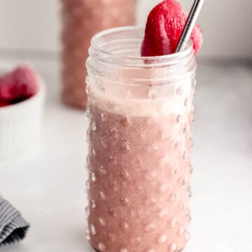 Close up side view of smoothie in glass with another in the background.